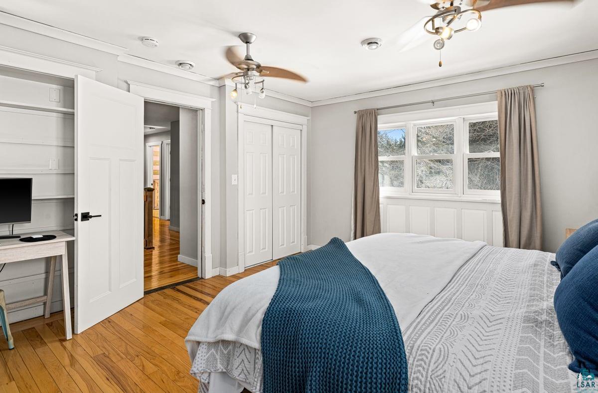 27 West Stark Road Esko, MN 55733 - Photo 26 of 47 Bedroom featuring light wood-type flooring, ornamental molding, ceiling fan, a desk, and two closets