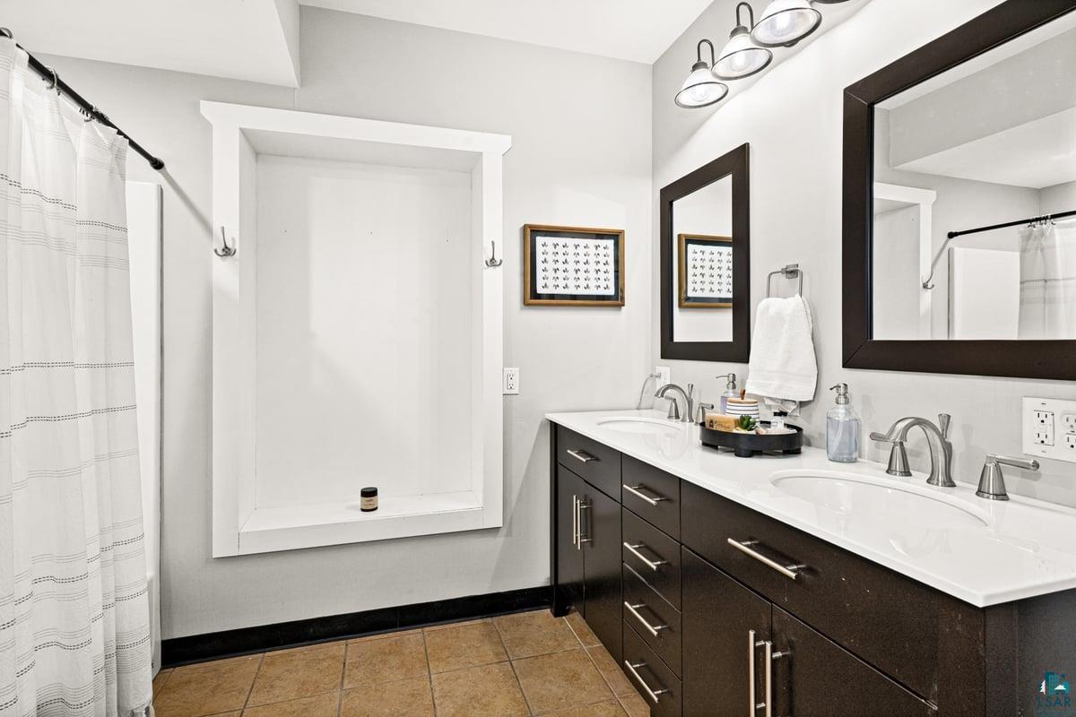 27 West Stark Road Esko, MN 55733 - Photo 33 of 47 Bathroom with curtained shower, double vanity, and light tile patterned floors