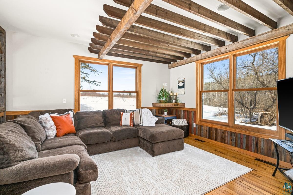 27 West Stark Road Esko, MN 55733 - Photo 8 of 47 Living room featuring a wainscoted wall, hardwood / wood-style floors, wood walls, and beam ceiling