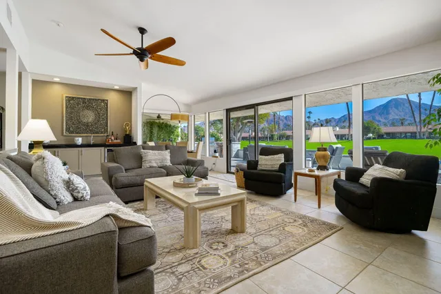 a living room with furniture ceiling fan and a large window
