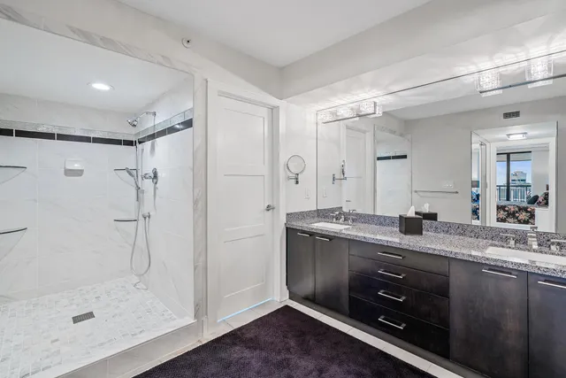 a bathroom with a granite countertop sink mirror and shower