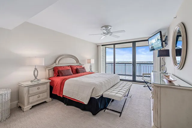 a bedroom with a bed a bookshelf and a large window