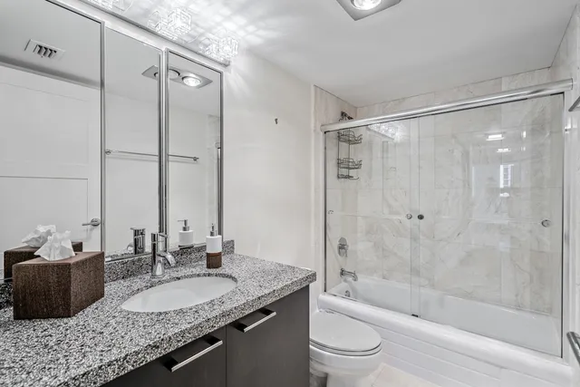 a bathroom with a granite countertop sink a toilet and shower