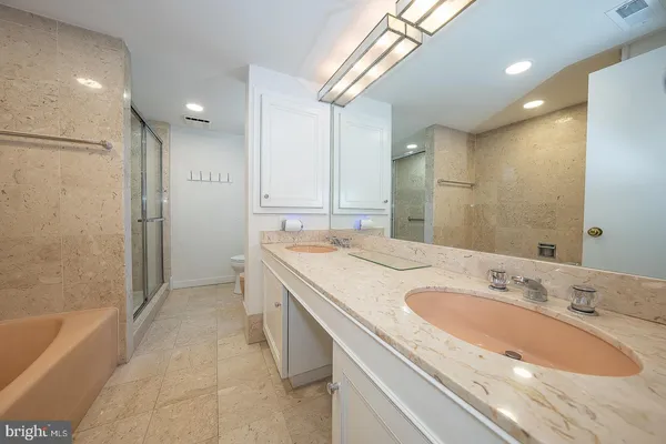 a bathroom with a granite countertop sink a mirror a bathtub and shower