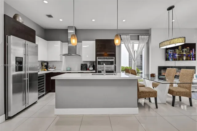 a kitchen with stainless steel appliances granite countertop a refrigerator oven a sink dishwasher a dining table and chairs with wooden floor