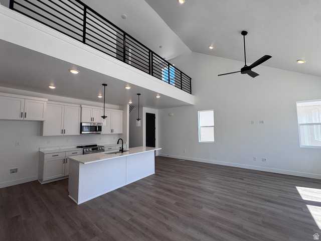 1301 1475 East, Unit 33 Payson, UT 84651 - Photo 6 of 10 Open-concept living space featuring a kitchen with white cabinetry and a central island, wood-finish flooring, vaulted ceilings, and a black ceiling fan