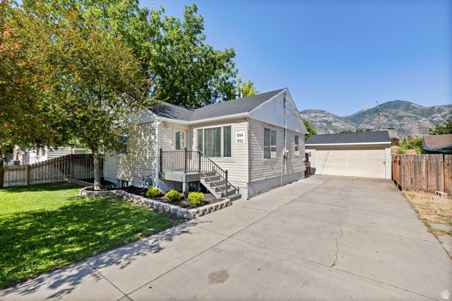 594 850 West Provo, UT 84601 - Photo 32 of 33 Single-story residence featuring light-colored siding, an inviting front porch with black railings, and a manicured lawn with mature trees