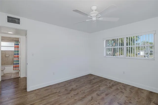 a view of empty room with wooden floor and fan