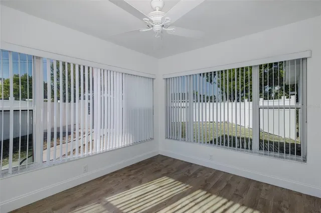 a view of a hallway to a room with wooden floor and cabinet