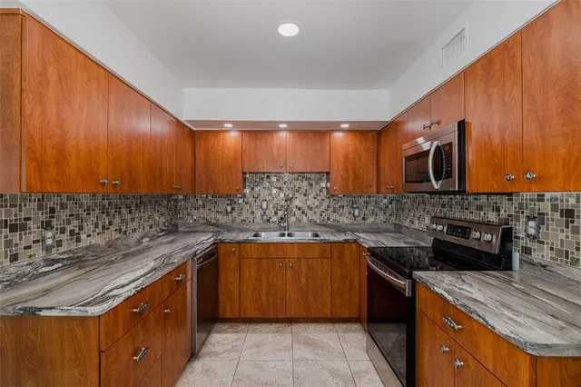 a kitchen with stainless steel appliances granite countertop wooden cabinets and a sink