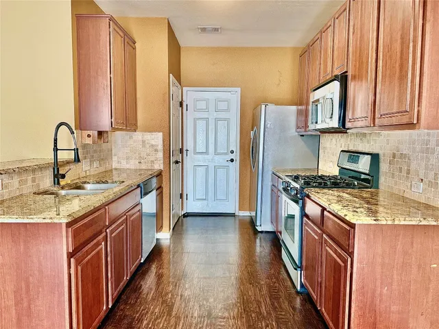 a kitchen with stainless steel appliances granite countertop a stove a sink dishwasher and a refrigerator