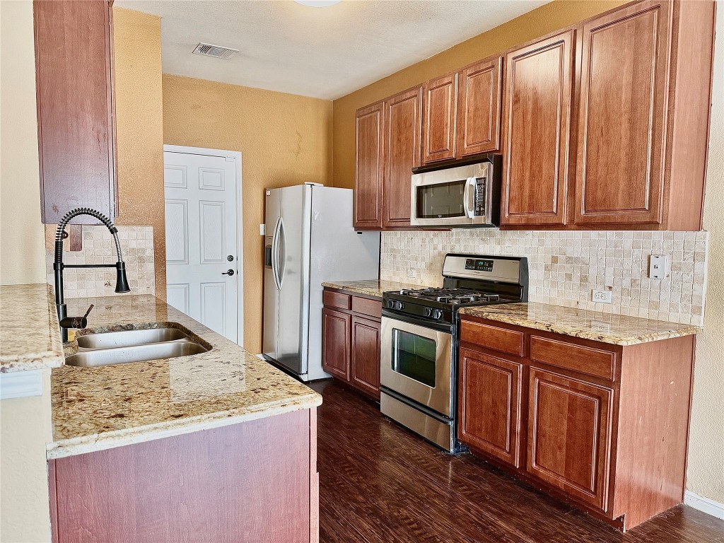 1900 Little Elm Trail, Unit 105 Cedar Park, TX 78613 - Photo 4 of 31 a kitchen with kitchen island granite countertop wooden cabinets stainless steel appliances and a sink