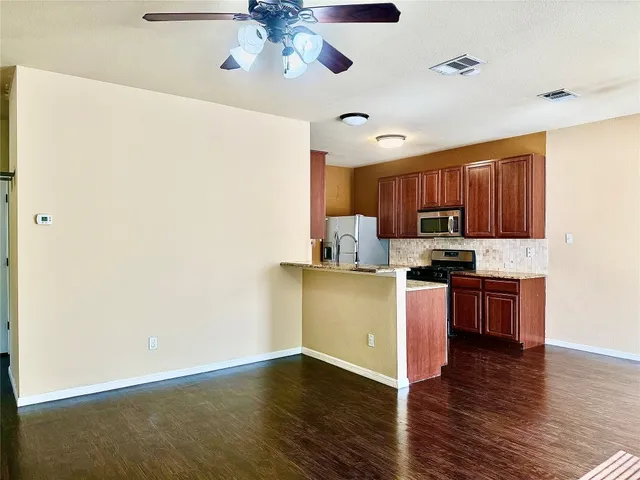 a kitchen with stainless steel appliances granite countertop a refrigerator a stove top oven a sink and dishwasher with wooden floor