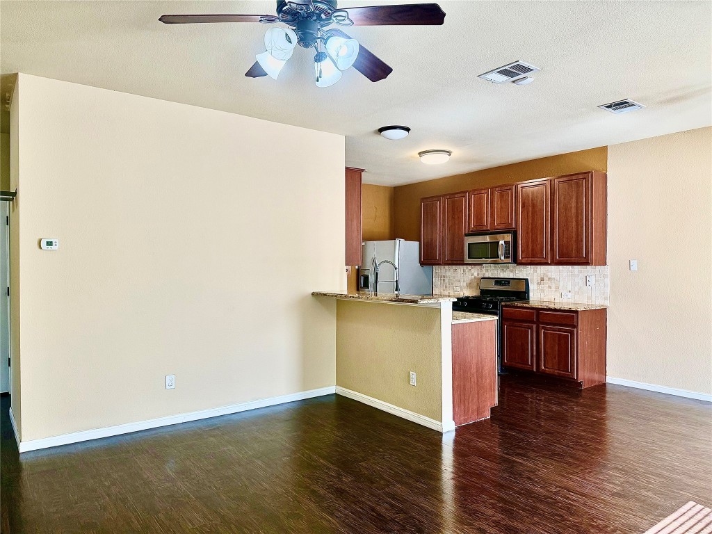 1900 Little Elm Trail, Unit 105 Cedar Park, TX 78613 - Photo 5 of 31 a kitchen with stainless steel appliances granite countertop a refrigerator a stove top oven a sink and dishwasher with wooden floor