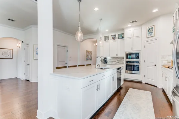 a large white kitchen with a large window a sink and stainless steel appliances