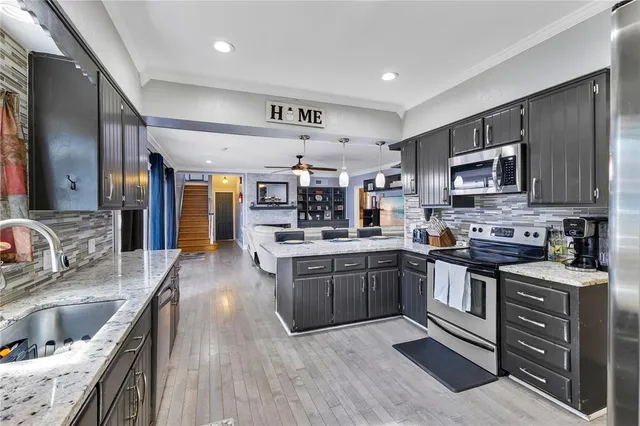 a kitchen with stainless steel appliances granite countertop a sink dishwasher stove and microwave with wooden floor