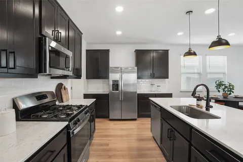 a kitchen with stainless steel appliances granite countertop a sink a stove oven a counter space and cabinets