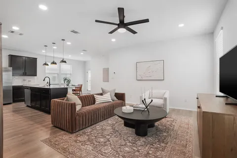 a living room with furniture a flat screen tv and kitchen view