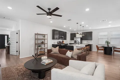 a living room with furniture kitchen view and a wooden floor