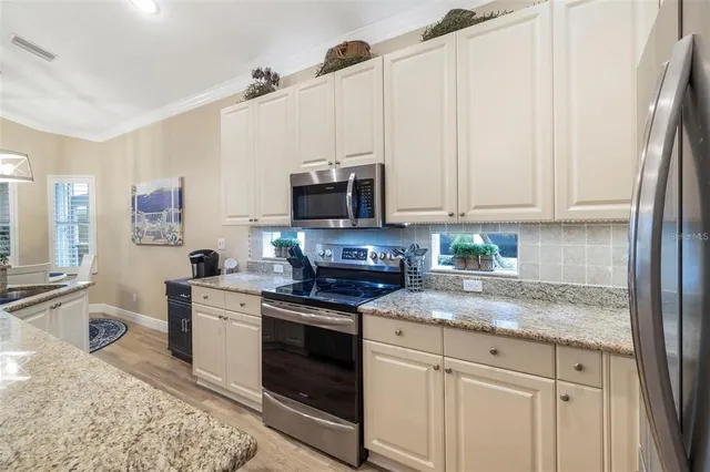 an open kitchen with granite countertop a sink a counter top space appliances and cabinets