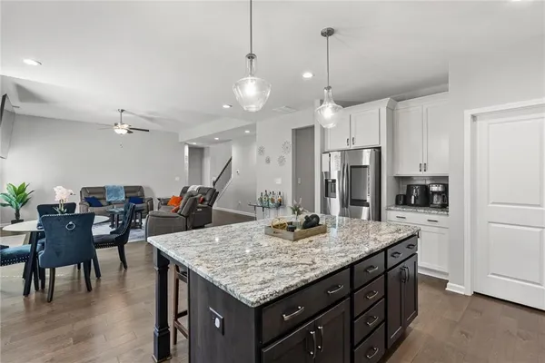 a kitchen with granite countertop a table chairs stainless steel appliances and cabinets