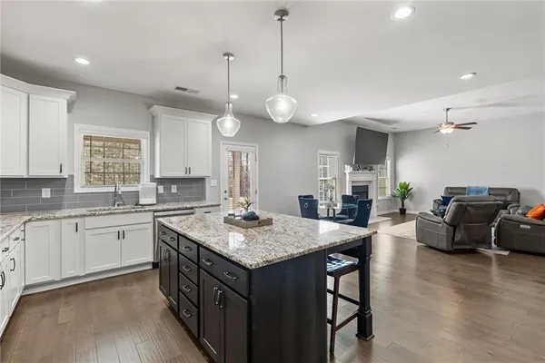 a kitchen with a stove a sink a dining table and chairs with wooden floor