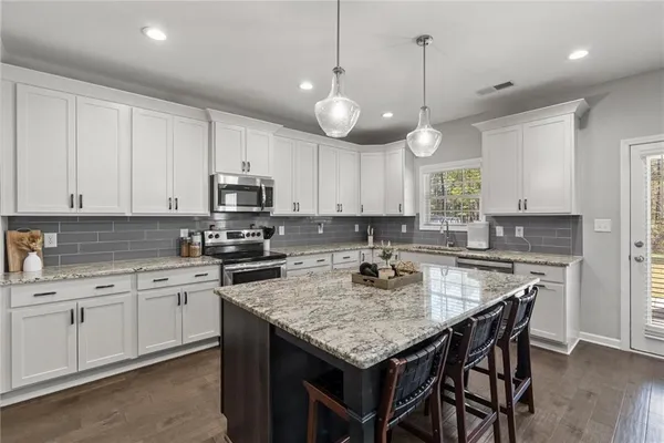 a kitchen with a center island white cabinets and stainless steel appliances