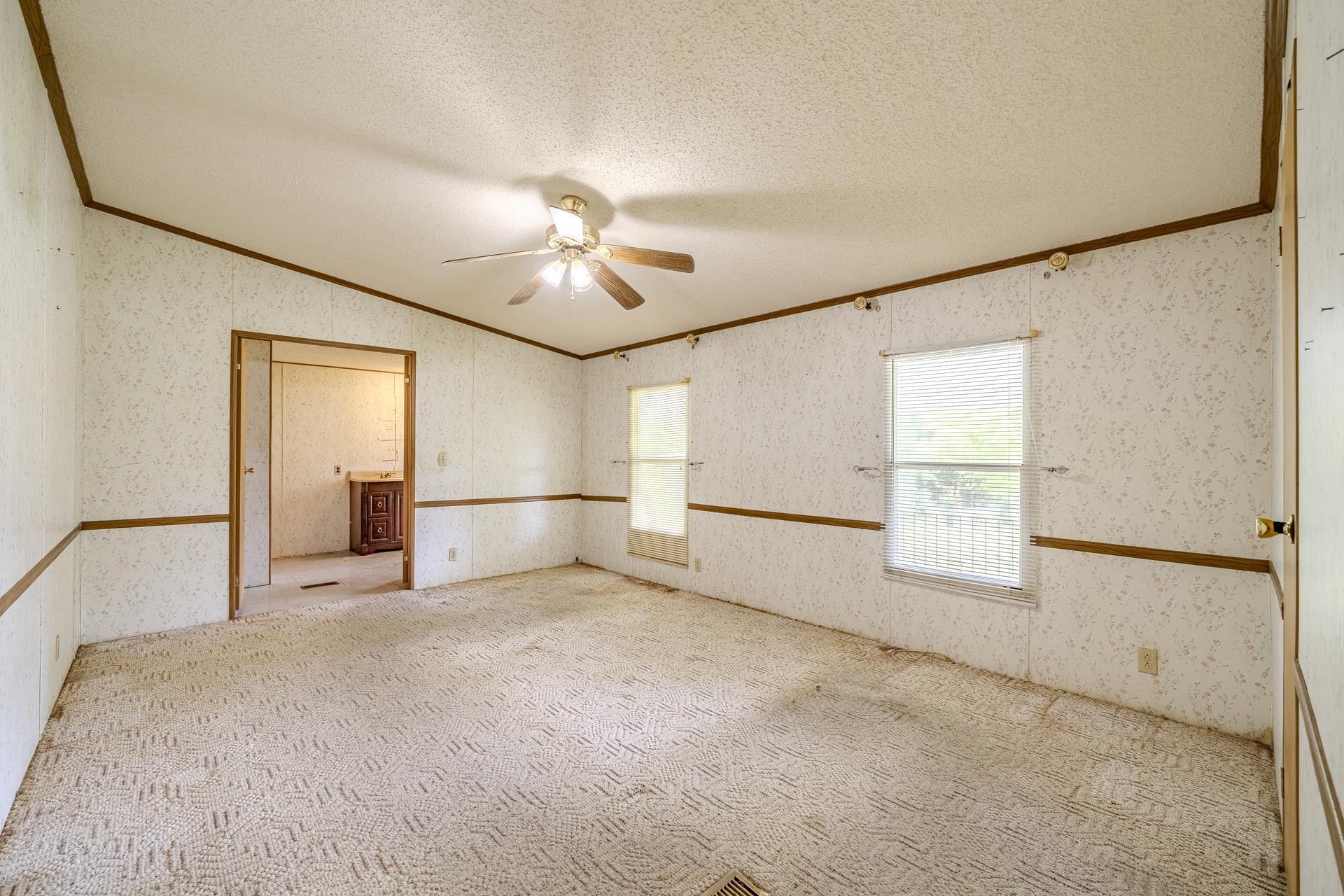 859 Old Morris Chapel Road Adamsville, TN 38310 - Photo 18 of 39 Spacious room featuring patterned carpeting, two windows, and a ceiling fan with integrated lighting