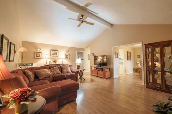 a living room with furniture kitchen view and a wooden floor