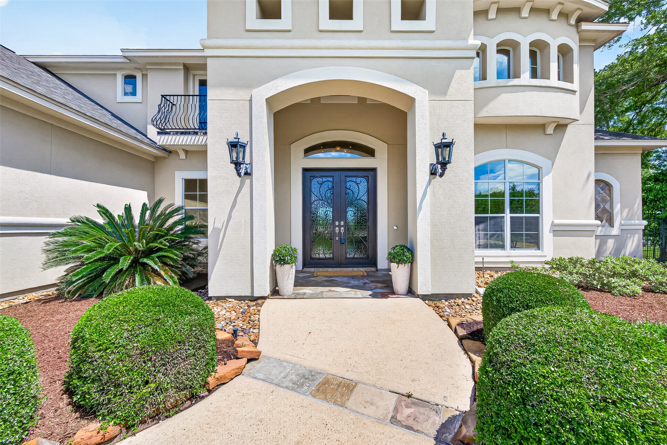 25626 Windy Isle Court Spring, TX 77389 - Photo 3 of 45 The entrance has a grand archway, decorative double doors, and stylish sconces, creating an inviting and upscale curb appeal.