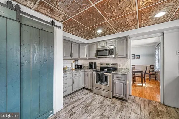 a kitchen with stainless steel appliances granite countertop a stove top oven a sink dishwasher a dining table and chairs with wooden floor