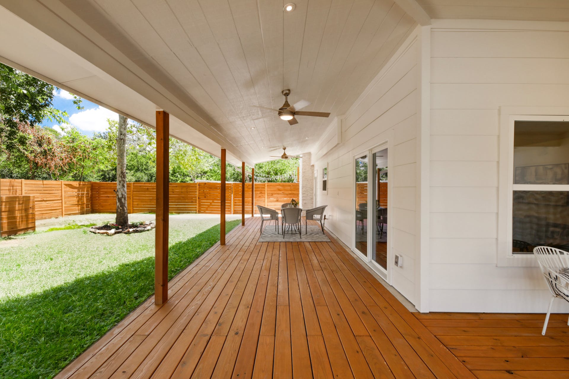 13207 Fencerail Road Manchaca, TX 78652 - Photo 2 of 36 Wooden terrace with a ceiling fan, outdoor dining area, and a fenced backyard