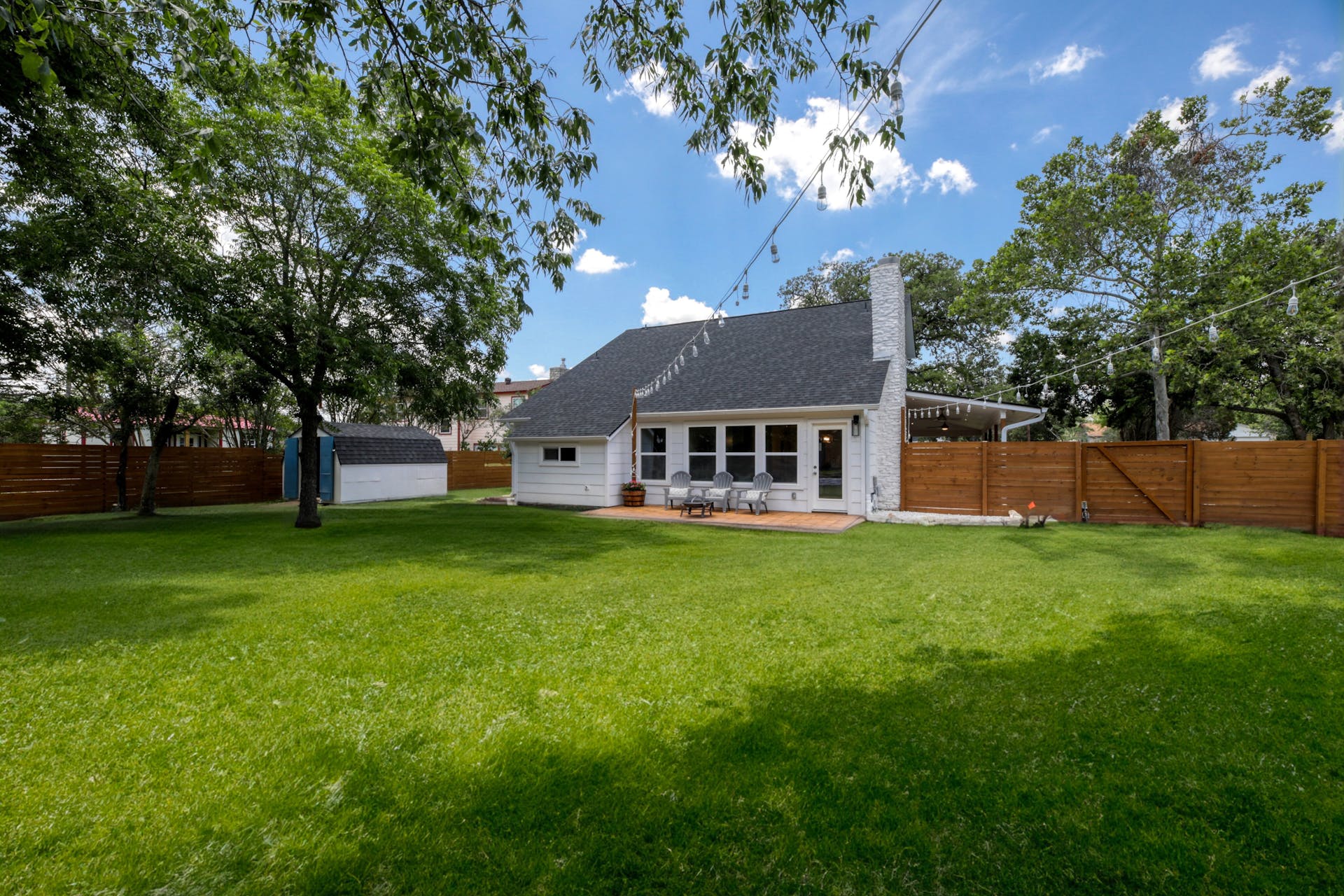13207 Fencerail Road Manchaca, TX 78652 - Photo 26 of 36 Rear view of house with a patio, a fenced backyard, a chimney, and a shed