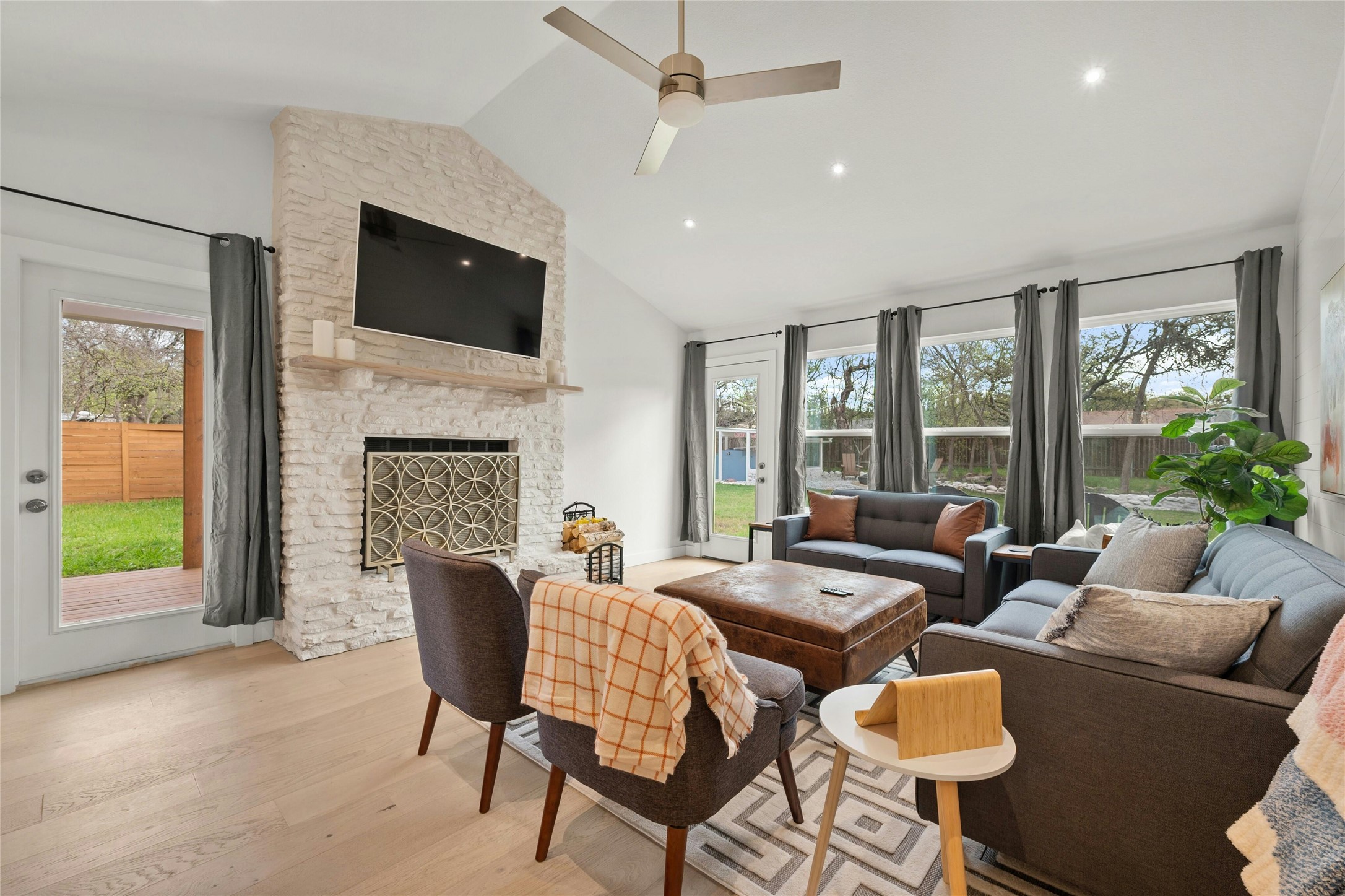 13207 Fencerail Road Manchaca, TX 78652 - Photo 6 of 36 Living room featuring white oak wood floors and a stone fireplace with a mechanical TV mount that can lower to a comfortable viewing height