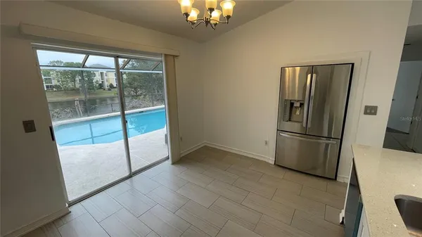 a view of a refrigerator in kitchen and an empty room