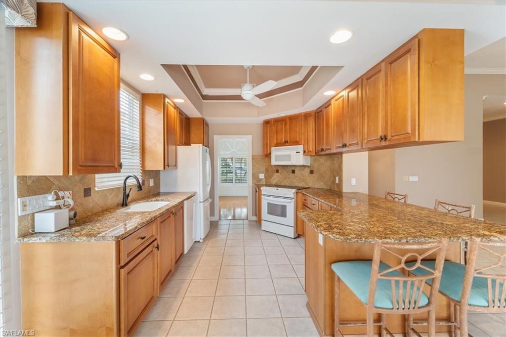 3956 Isla Ciudad Court Naples, FL 34109 - Photo 12 of 31 a kitchen with stainless steel appliances granite countertop a sink and a refrigerator