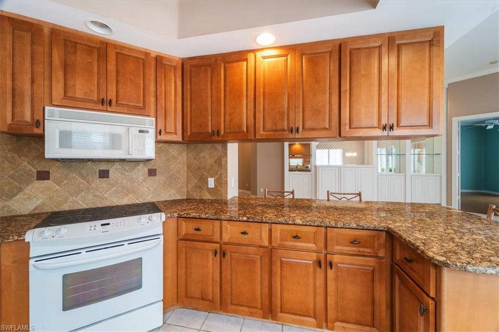 3956 Isla Ciudad Court Naples, FL 34109 - Photo 13 of 31 a kitchen with granite countertop wooden cabinets and a sink