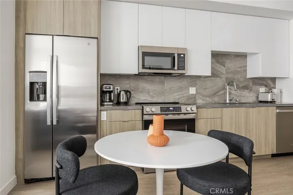 a kitchen with stainless steel appliances granite countertop a dining table chairs and a refrigerator