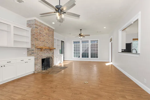a view of an empty room with window and wooden floor
