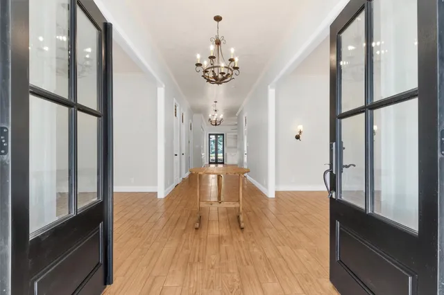an empty room with wooden floor chandelier fan and windows