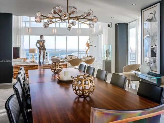 a view of a dining room with furniture a chandelier and large windows