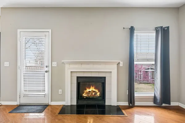 a view of an empty room with wooden floor fridge and a window