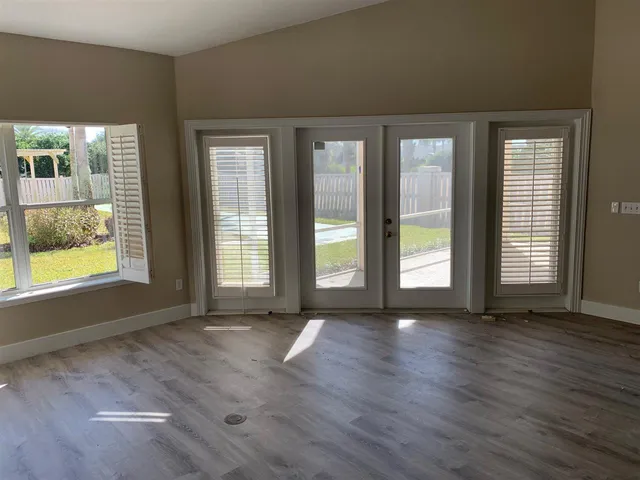 a view of an empty room with wooden floor and a window