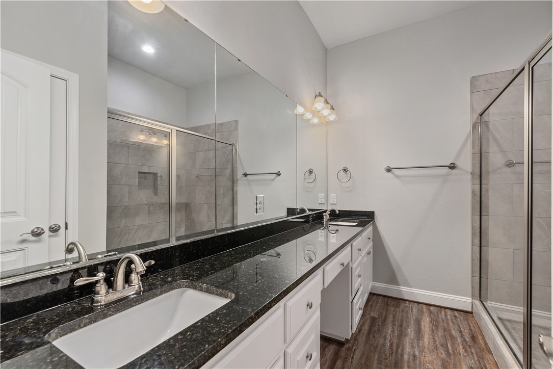 401 North Main Street, Unit 206 Bryan, TX 77803 - Photo 14 of 20 a bathroom with a granite countertop sink a mirror and a shower