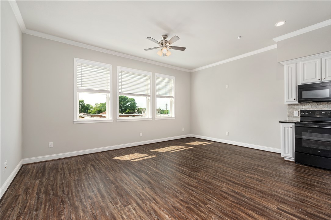 401 North Main Street, Unit 206 Bryan, TX 77803 - Photo 6 of 20 an empty room with wooden floor a chandelier fan and windows