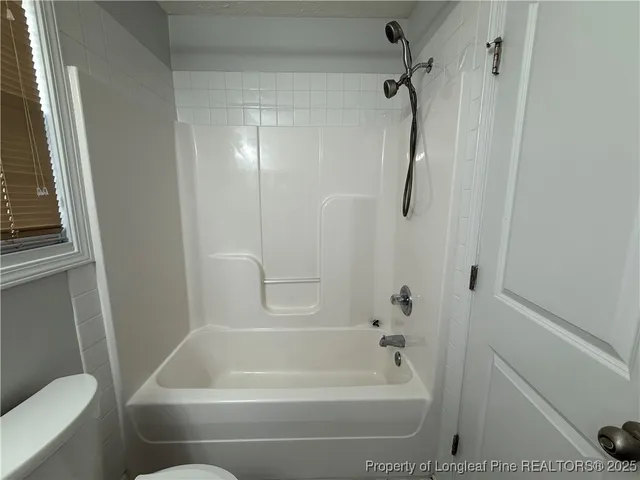an empty room with windows and chandelier fan