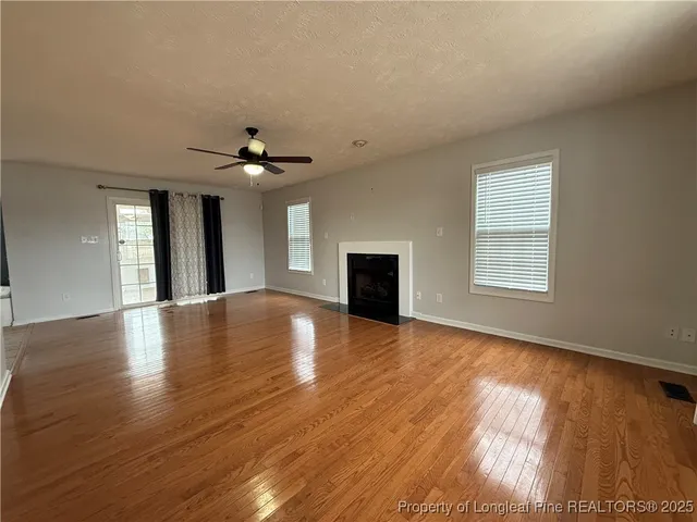 a view of an empty room with window and wooden floor