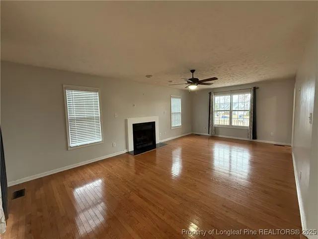 an empty room with wooden floor chandelier and windows