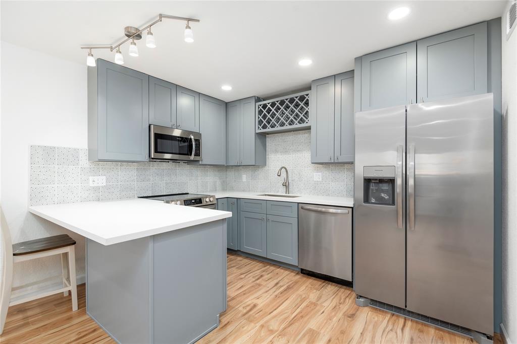 a kitchen with a sink stainless steel appliances and white cabinet