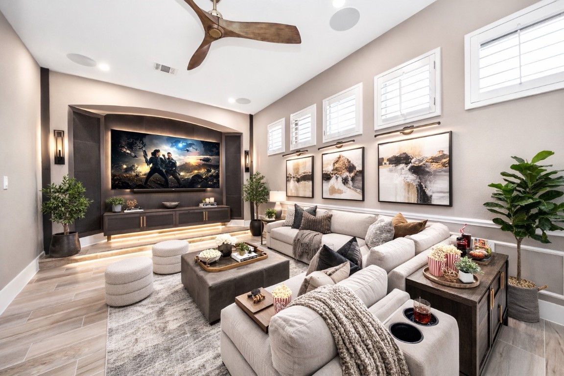 2211 Braer Ridge Drive Katy, TX 77494 - Photo 13 of 50 This photo showcases a stylish home theater room with a large screen, cozy sectional seating, and modern decor. The space features elegant lighting, wall art, and plants, creating a comfortable and inviting atmosphere.